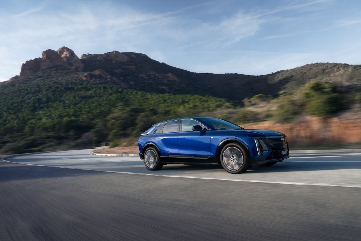 Front three quarter view of a Cadillac Lyriq, an award-winning luxury electric car, driving through an urban environment.