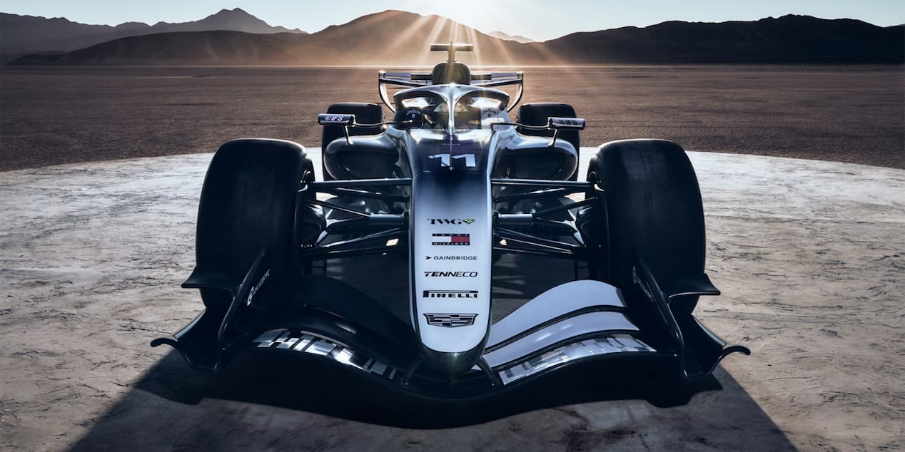Front-on view of Cadillac's F1 racecar on a desert racetrack, the setting sun behind casting long shadows.