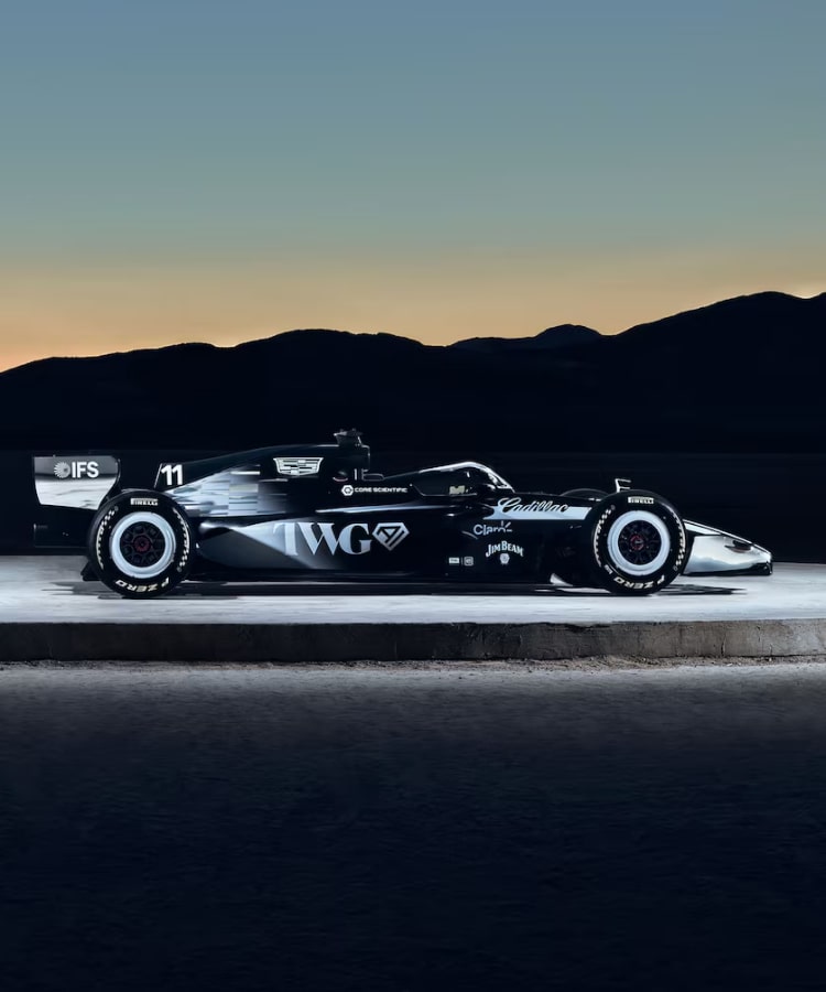 In profile, against a rocky desert skyline at dusk, two Cadillac F1 cars are back to back. Like duelists about to clash.