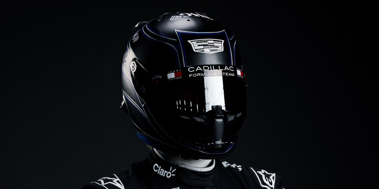 A Forumla 1 driver's head in glossy black Cadillac racing helmet against a dark studio background