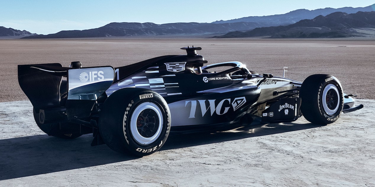 Three-quarter rear view of a Cadillac F1 car in a dramatic red-and-blue desert landscape.