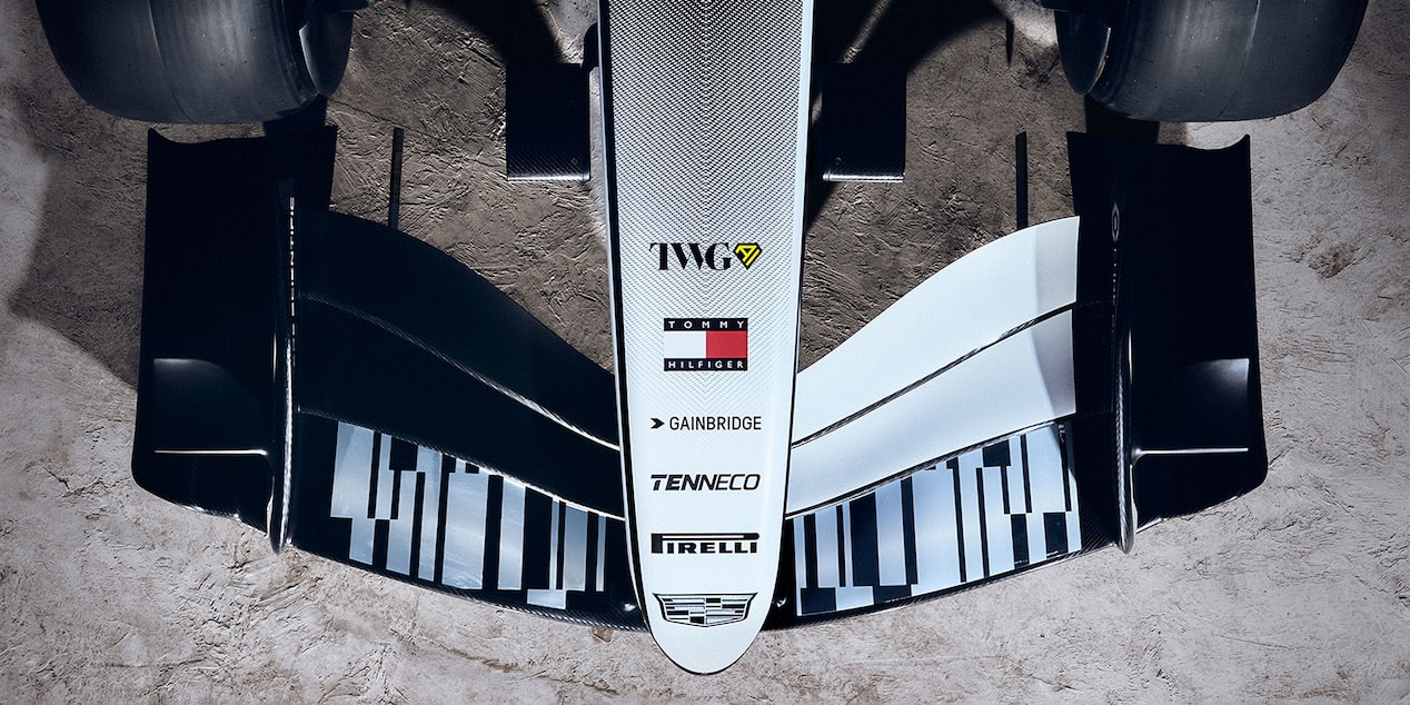 Aerial view of the Cadillac F1 car’s nose adorned with sponsors’ names, and front wing, with grey rocky surface beneath.