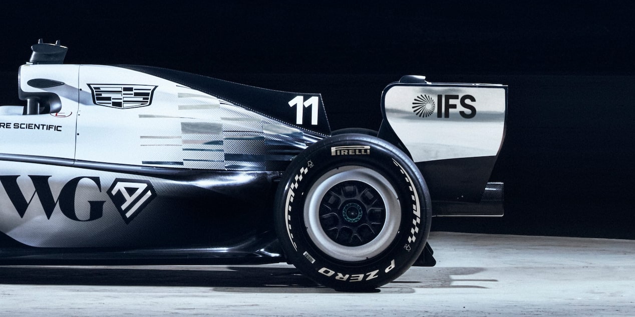 Rear half of Cadillac’s F1 car, in profile, with sponsor’s names. On concrete floor with ‘General motors’ on wall behind.