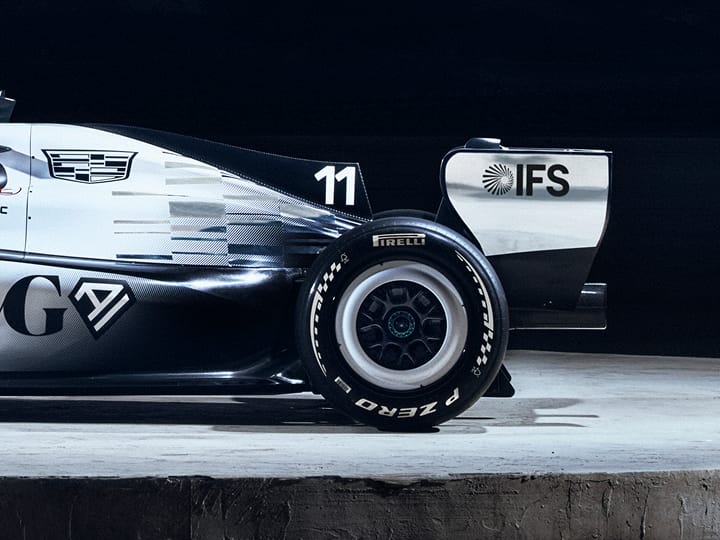 Rear half of Cadillac’s F1 car, in profile, with sponsor’s names. On concrete floor with ‘General motors’ on wall behind.