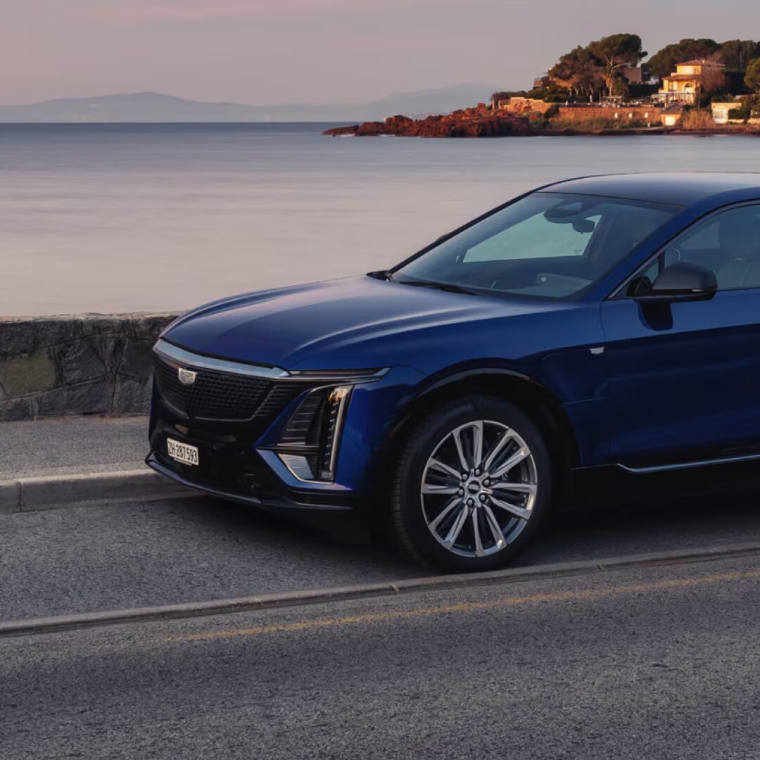 Dreiviertelansicht der Frontpartie des Cadillac LYRIQ in Opulent Blue Metallic auf einer Küstenstraße.