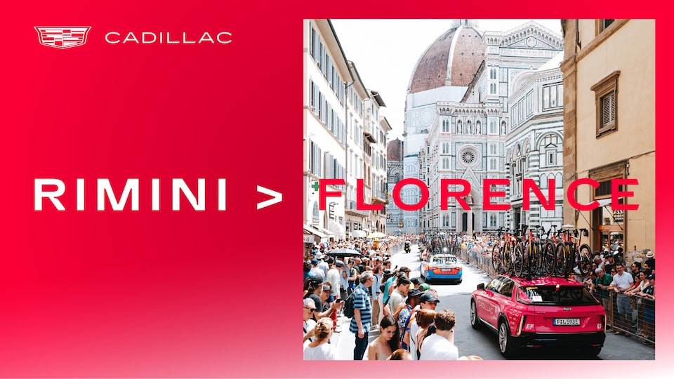 Pink Cadillac LYRIQ support car drives through crowds of fans in the heart of Florence on the first stage of the Tour De France with EF Pro Cycling team.​