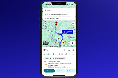 Smartphone displaying a navigation map with a planned driving route, estimated travel time, and electric vehicle charging stops.