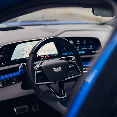 Interior view of the Cadillac LYRIQ showing the steering wheel and wide digital display across the dashboard.