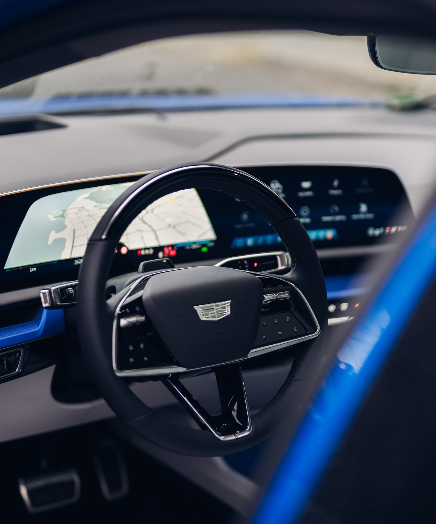 Vue de l’intérieur du Cadillac LYRIQ montrant le volant et un large écran numérique sur le tableau de bord.