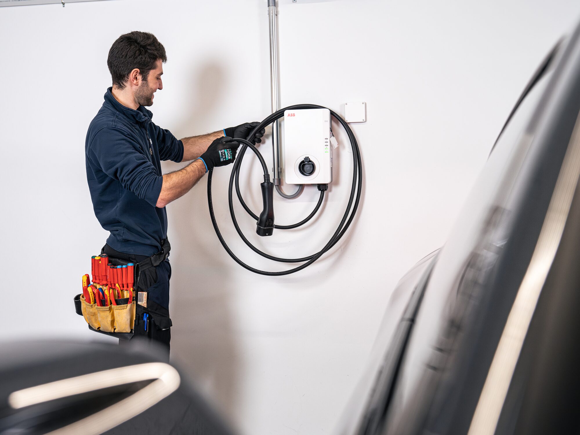 Technicien installant une unité de recharge de véhicule électrique murale à l'intérieur d'un garage.
