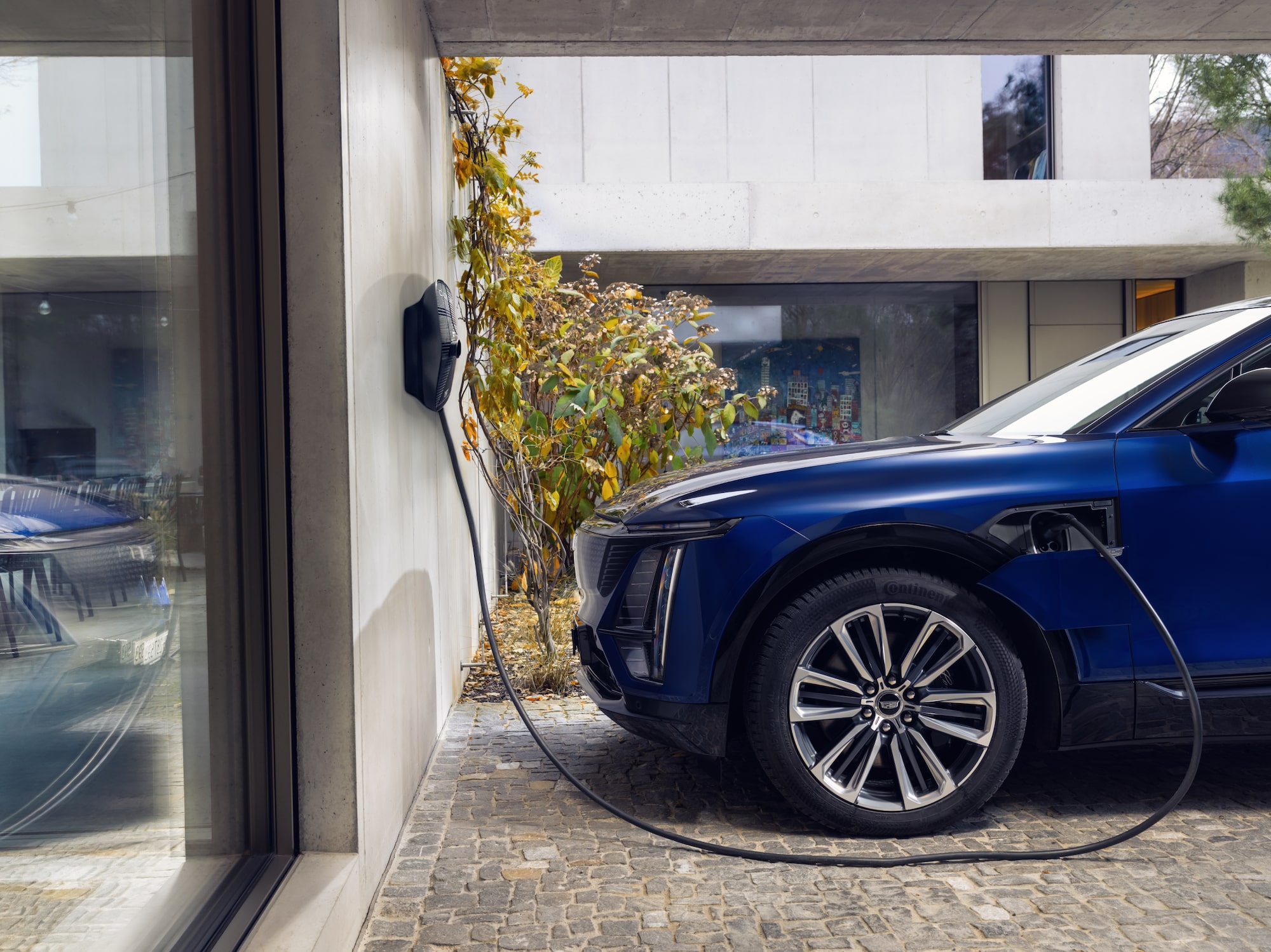 SUV électrique Cadillac LYRIQ en charge, connecté à une station en bord de route dans un environnement urbain.