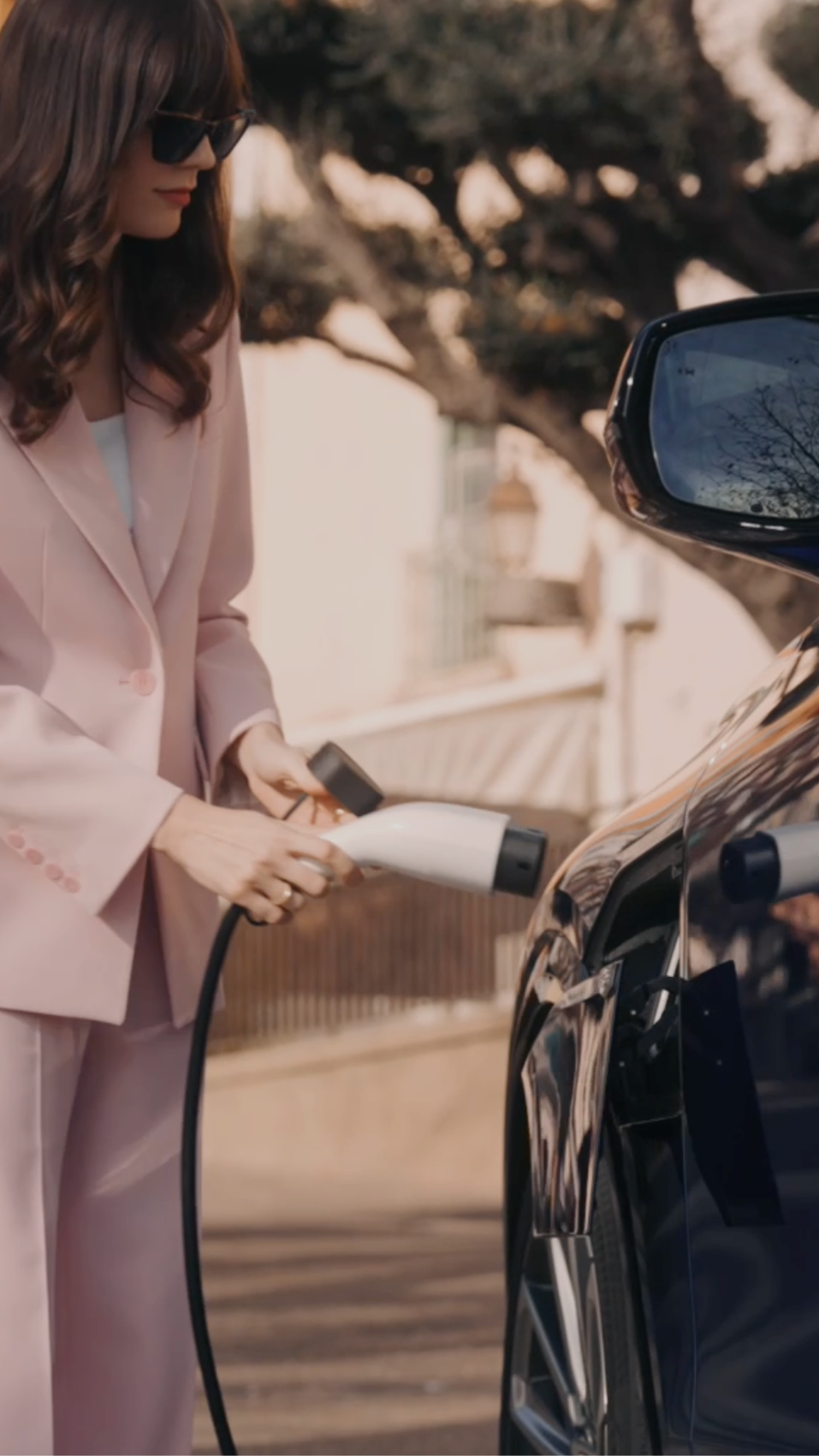 Femme débranchant un SUV électrique Cadillac LYRIQ stationné dans une rue résidentielle.