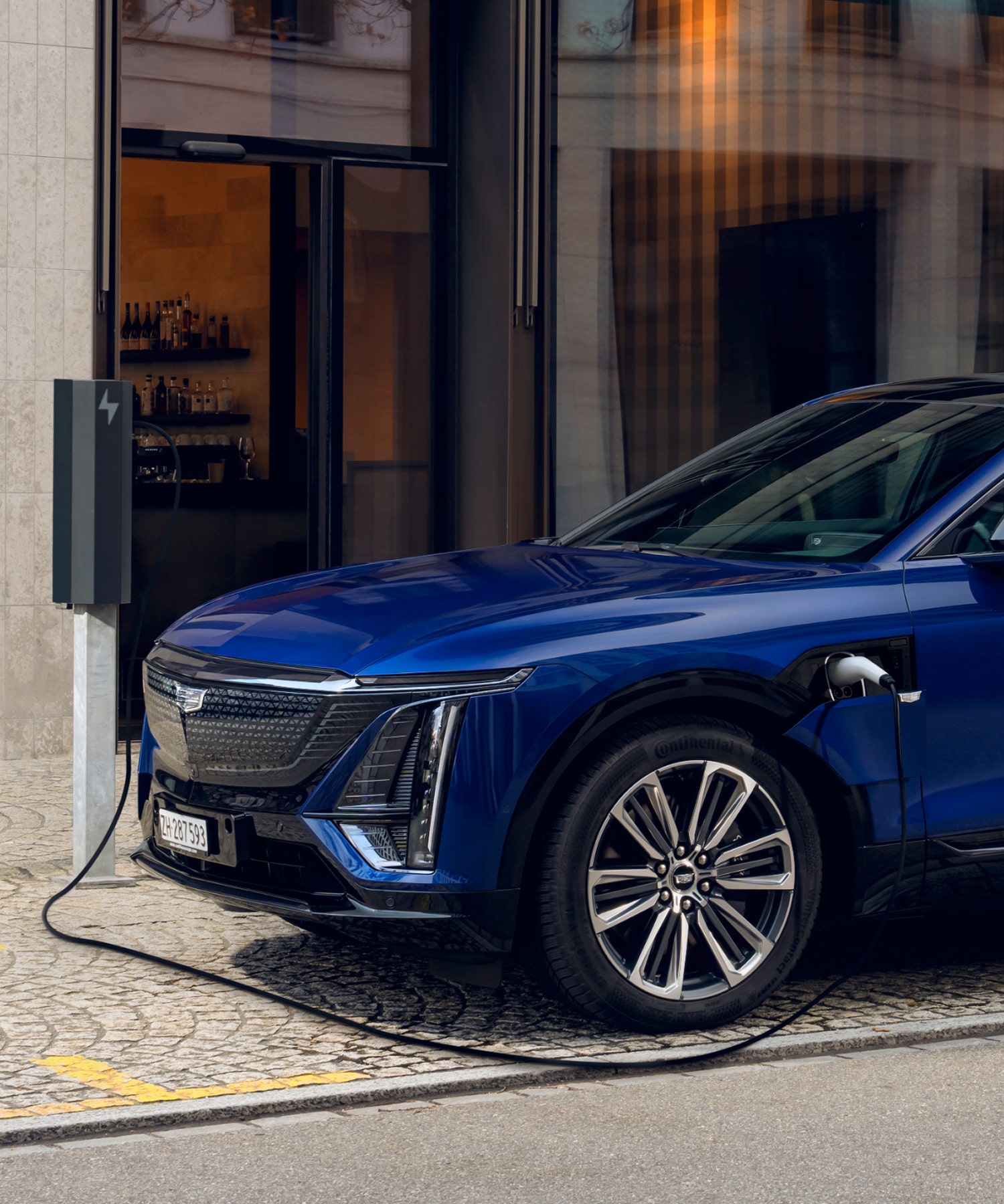 SUV électrique Cadillac LYRIQ en charge, connecté à une station en bord de route dans un environnement urbain.